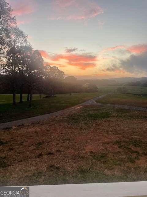 yard at dusk featuring a rural view