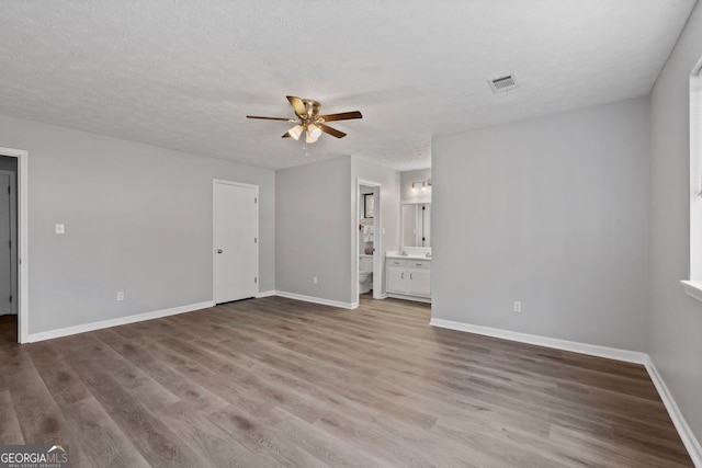 empty room with hardwood / wood-style floors, ceiling fan, and a textured ceiling