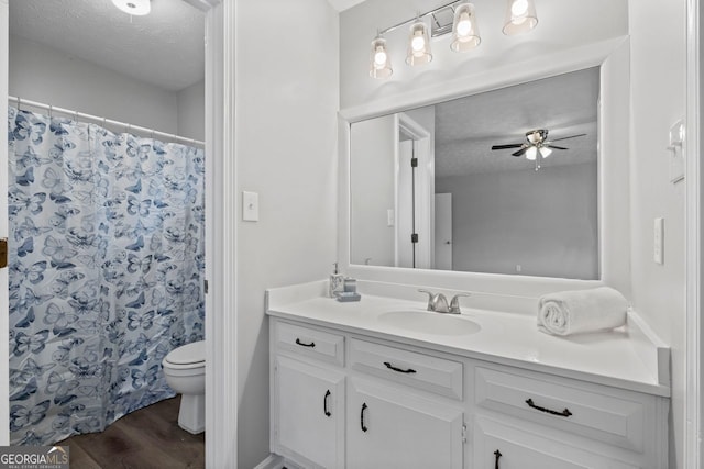 bathroom featuring vanity, a textured ceiling, ceiling fan, hardwood / wood-style floors, and toilet