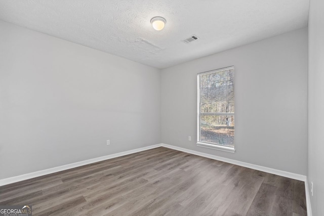 empty room with wood-type flooring and a textured ceiling