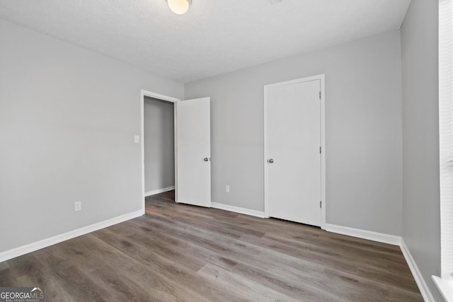 unfurnished bedroom with a closet, hardwood / wood-style floors, and a textured ceiling