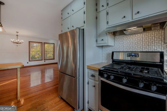 kitchen featuring decorative backsplash, appliances with stainless steel finishes, pendant lighting, light hardwood / wood-style flooring, and a chandelier