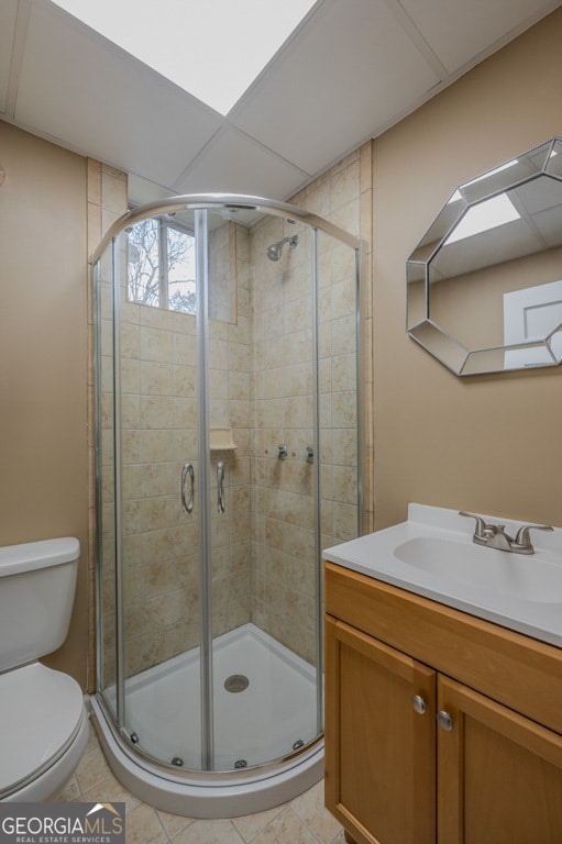 bathroom with tile patterned flooring, vanity, toilet, and walk in shower