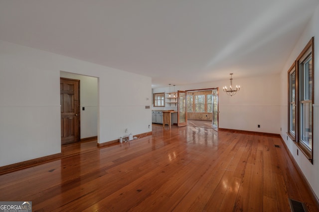 unfurnished living room with a chandelier and light hardwood / wood-style flooring