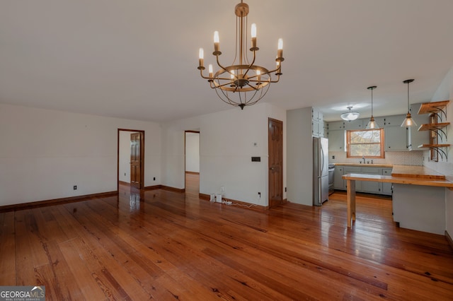 kitchen with wood counters, backsplash, hardwood / wood-style flooring, decorative light fixtures, and stainless steel refrigerator