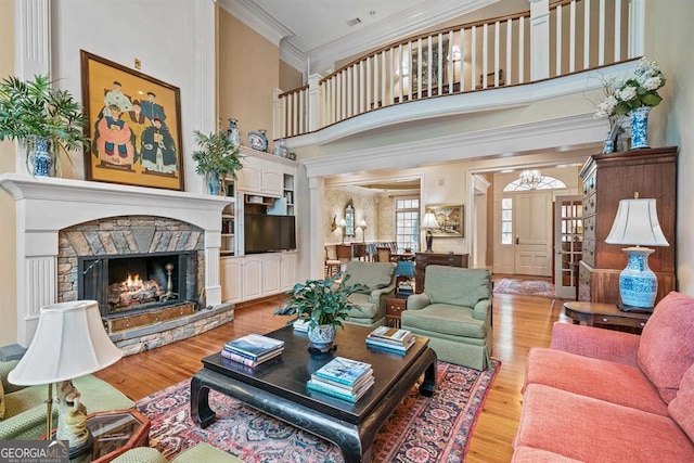 living room with crown molding, a towering ceiling, a fireplace, and light hardwood / wood-style flooring