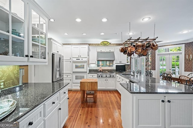 kitchen featuring white cabinetry, sink, stainless steel appliances, dark stone counters, and light hardwood / wood-style floors