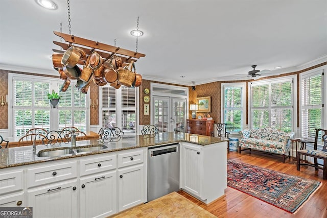 kitchen featuring light wood-type flooring, sink, dark stone countertops, dishwasher, and white cabinetry