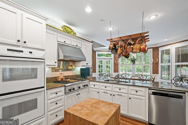 kitchen featuring sink, light hardwood / wood-style flooring, dark stone counters, white cabinets, and appliances with stainless steel finishes