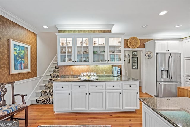 kitchen with white cabinetry, stainless steel fridge with ice dispenser, dark stone counters, and light wood-type flooring