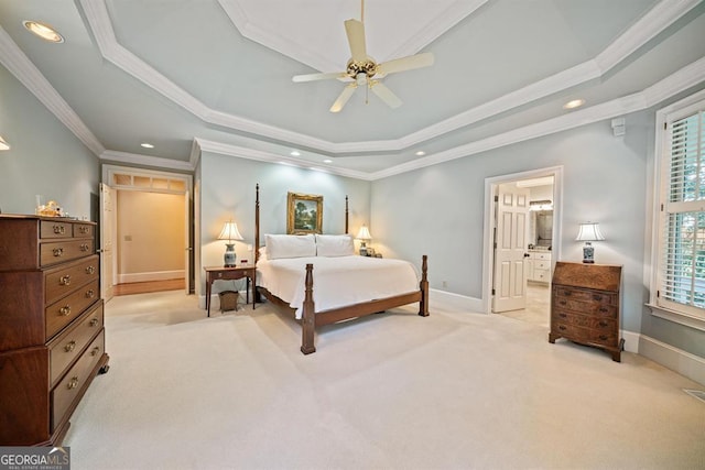 carpeted bedroom with ceiling fan, a raised ceiling, crown molding, and ensuite bath