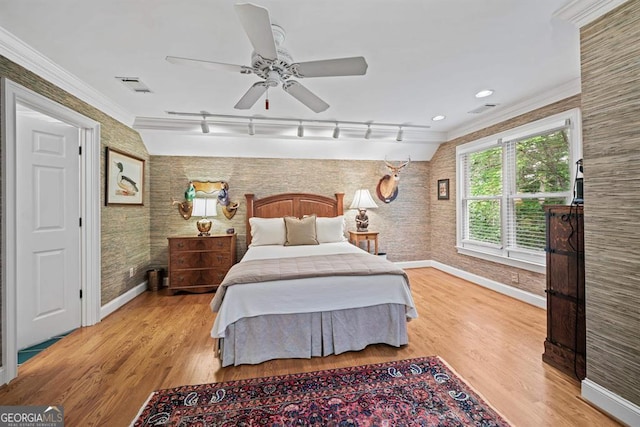 bedroom with rail lighting, light hardwood / wood-style floors, ceiling fan, and crown molding