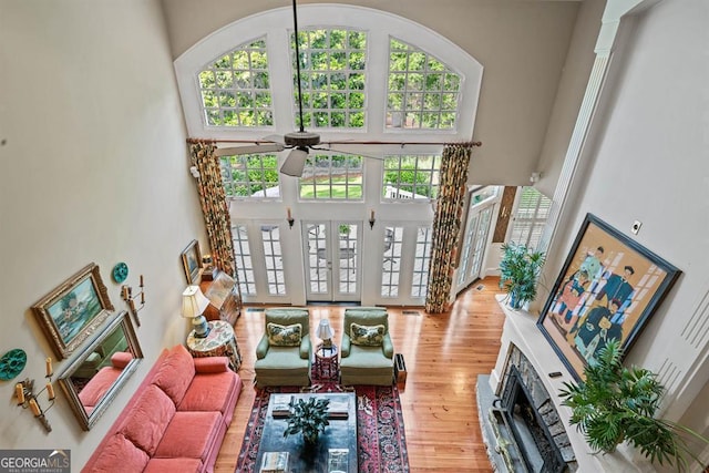 living room featuring ceiling fan, wood-type flooring, and a high ceiling