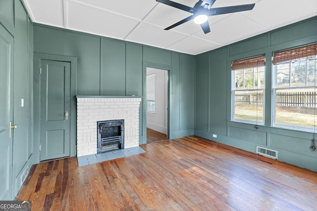 unfurnished living room with ceiling fan, wood-type flooring, and a fireplace