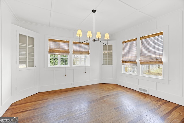 unfurnished dining area featuring hardwood / wood-style flooring and a chandelier