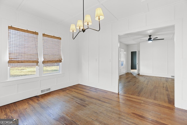 unfurnished dining area with dark wood-type flooring and ceiling fan with notable chandelier