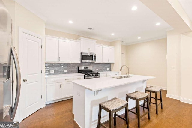 kitchen with a kitchen breakfast bar, light hardwood / wood-style floors, a center island with sink, white cabinets, and appliances with stainless steel finishes