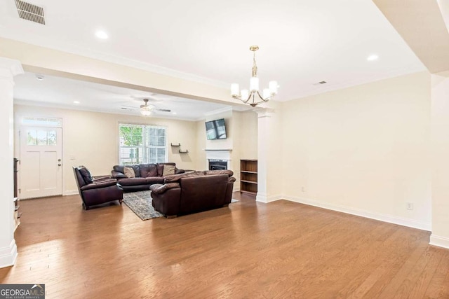 living room with ceiling fan with notable chandelier, light wood-type flooring, and ornamental molding