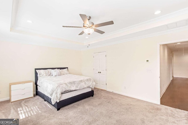 bedroom with a raised ceiling, ceiling fan, carpet floors, and ornamental molding