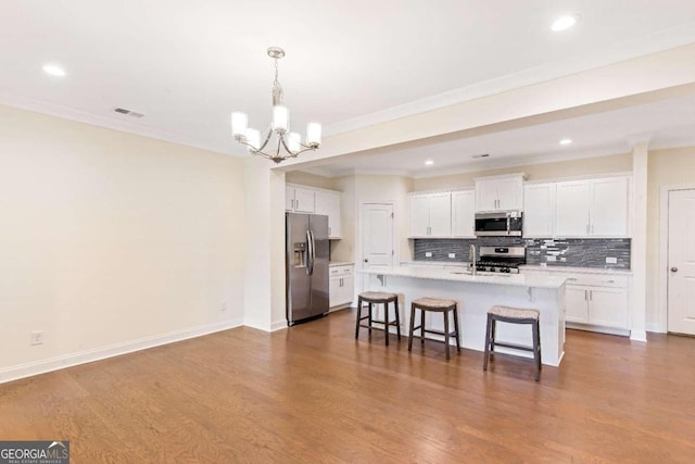 kitchen with white cabinetry, a breakfast bar, wood-type flooring, and appliances with stainless steel finishes