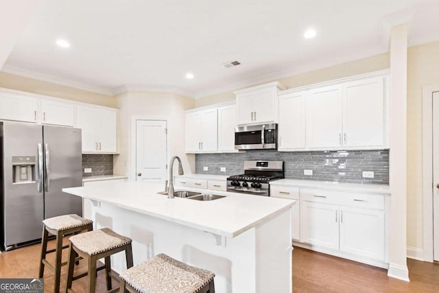 kitchen featuring sink, white cabinetry, stainless steel appliances, and an island with sink