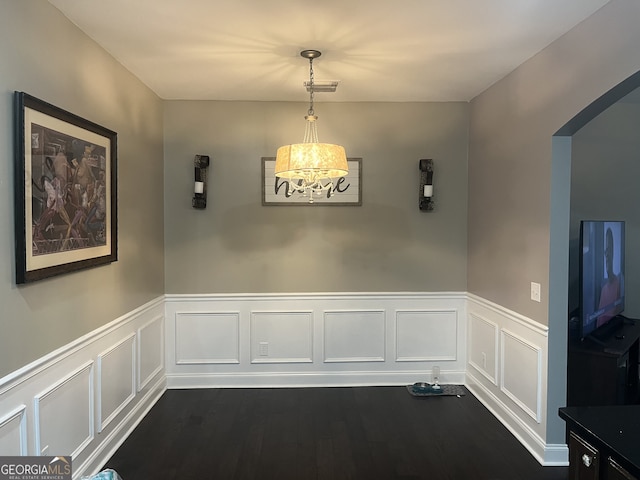 unfurnished dining area featuring a notable chandelier and dark hardwood / wood-style flooring