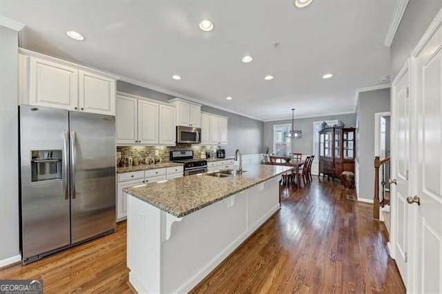 kitchen featuring light stone countertops, sink, a kitchen bar, a center island with sink, and appliances with stainless steel finishes