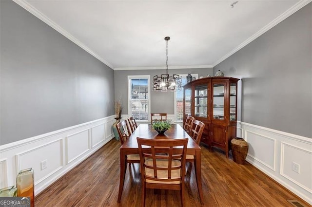 dining space featuring dark hardwood / wood-style flooring, crown molding, and an inviting chandelier