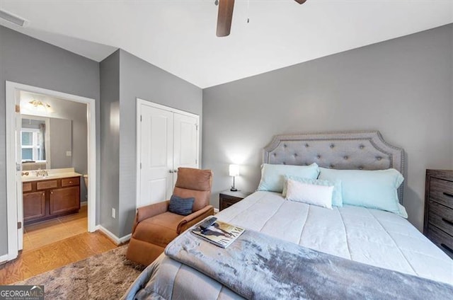 bedroom featuring ceiling fan, light hardwood / wood-style floors, lofted ceiling, and connected bathroom