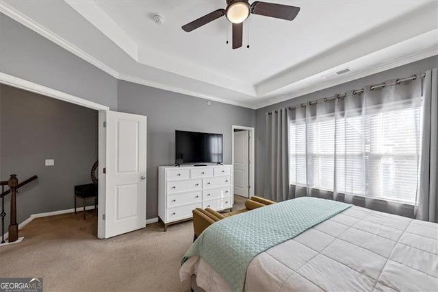 carpeted bedroom with a tray ceiling, ceiling fan, and crown molding