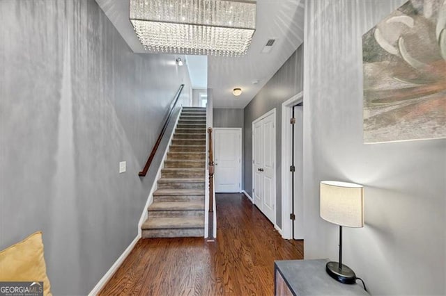 stairs with hardwood / wood-style floors and an inviting chandelier