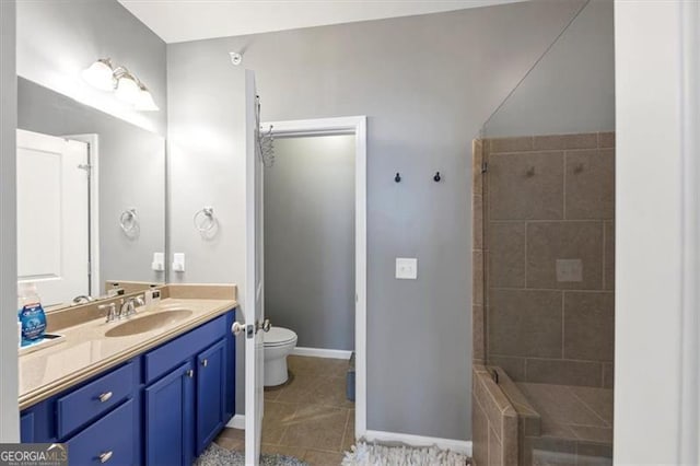 bathroom with a tile shower, tile patterned flooring, vanity, and toilet