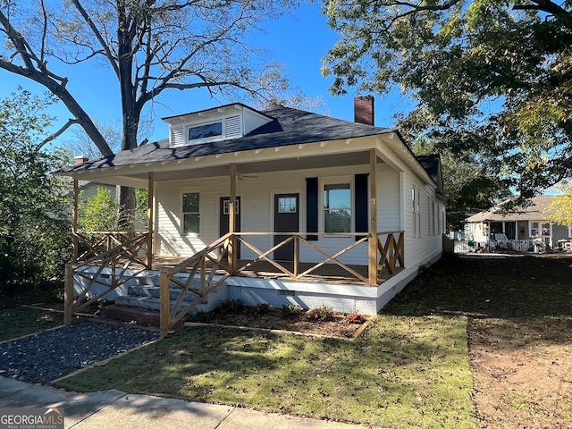 bungalow-style home featuring covered porch and a front yard