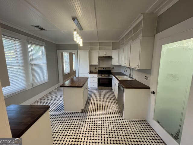 kitchen with decorative backsplash, stainless steel gas stove, white cabinetry, and butcher block counters