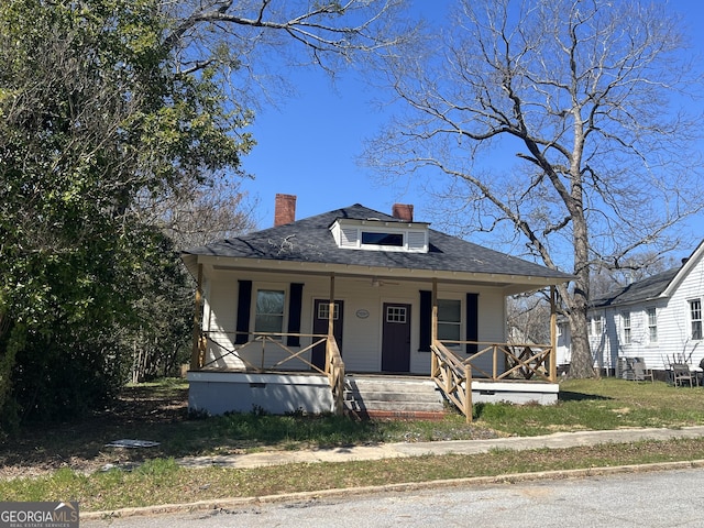 bungalow with a shingled roof, a chimney, and a porch