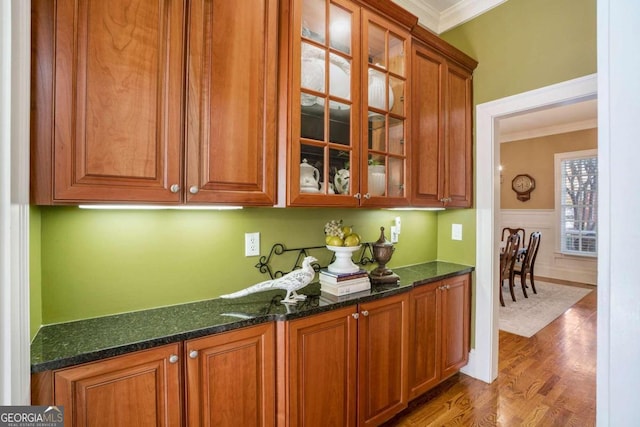 bar with hardwood / wood-style floors, ornamental molding, and dark stone countertops