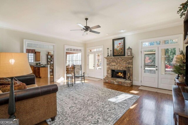 living room with french doors, ceiling fan, ornamental molding, a fireplace, and dark hardwood / wood-style flooring