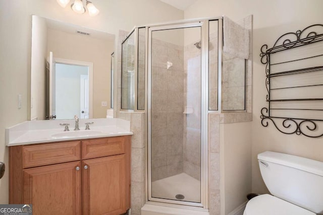 bathroom featuring an enclosed shower, vanity, and toilet