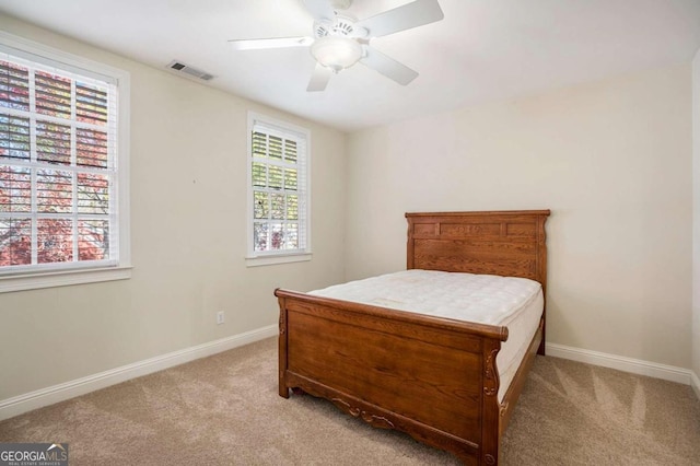 carpeted bedroom with ceiling fan and multiple windows