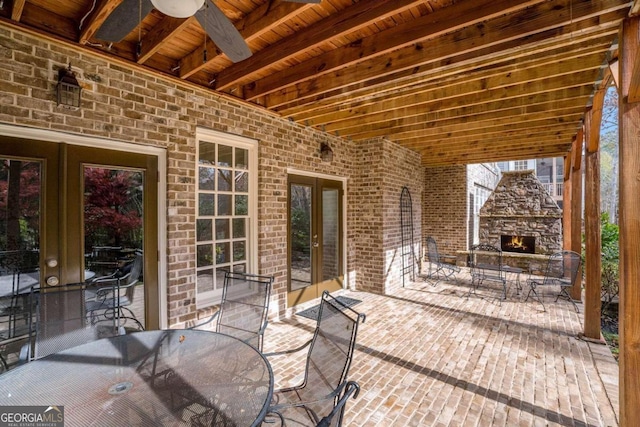 view of patio featuring an outdoor stone fireplace, french doors, and ceiling fan