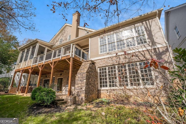 rear view of house with a lawn and a sunroom