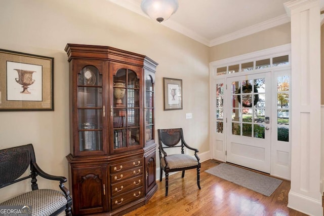 living area with wood-type flooring, ornate columns, and ornamental molding