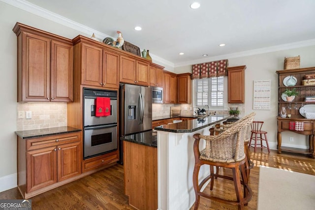 kitchen with dark stone counters, crown molding, decorative backsplash, appliances with stainless steel finishes, and dark hardwood / wood-style flooring