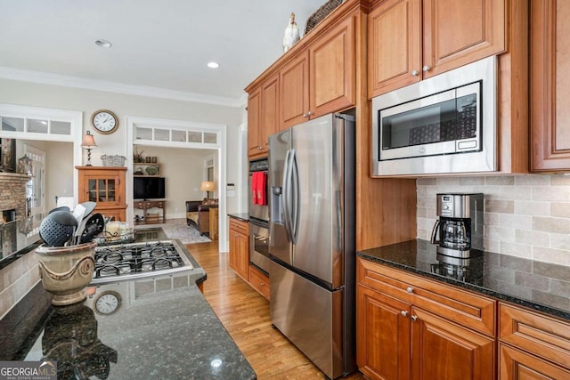 kitchen featuring backsplash, ornamental molding, light wood-type flooring, and appliances with stainless steel finishes