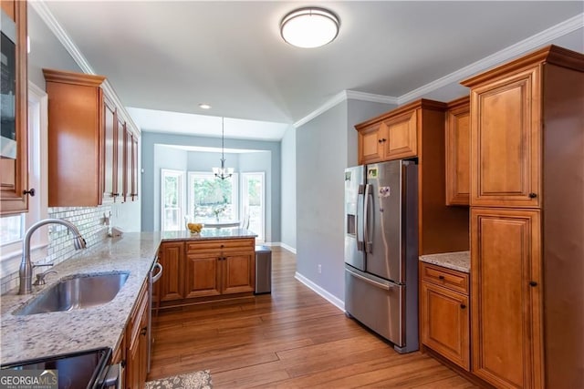 kitchen featuring light stone countertops, sink, hanging light fixtures, stainless steel appliances, and an inviting chandelier