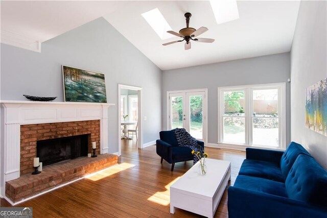 living room featuring a skylight, ceiling fan, a fireplace, and hardwood / wood-style flooring