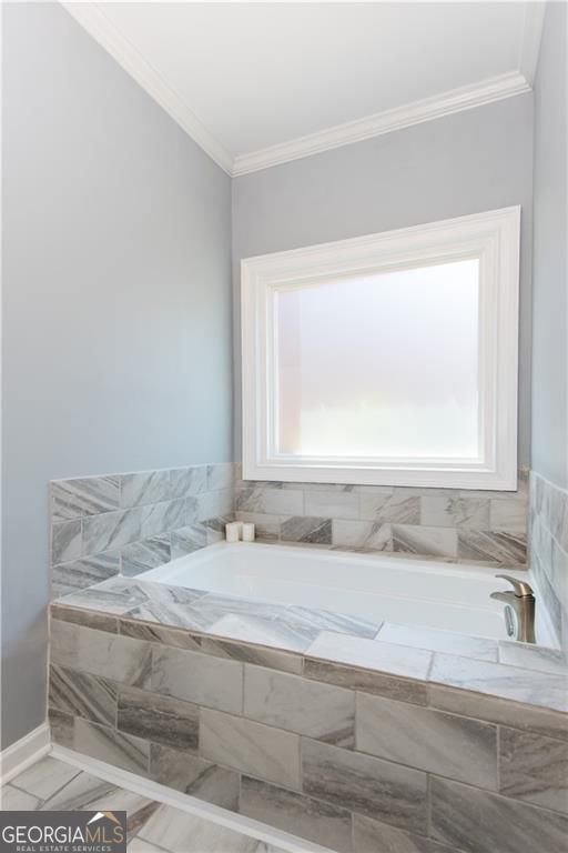 bathroom featuring crown molding and tiled bath