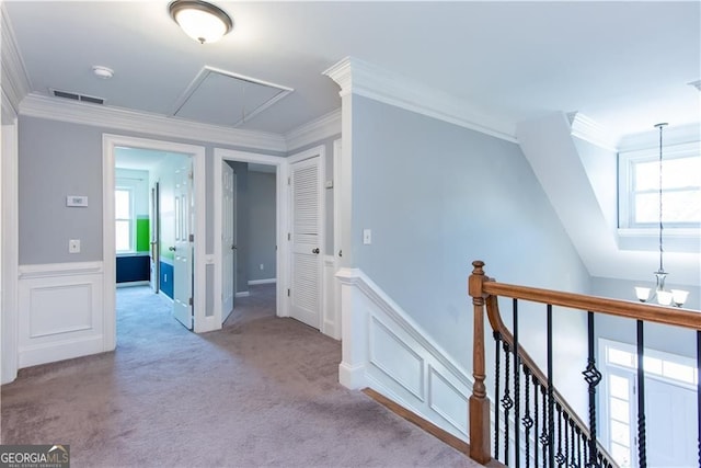 hall with a notable chandelier, ornamental molding, a wealth of natural light, and light colored carpet