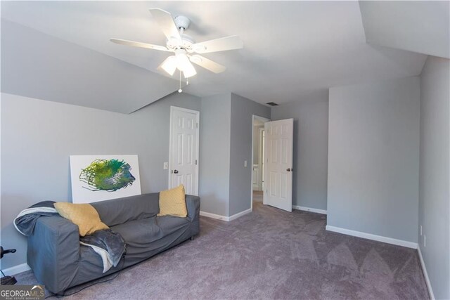 living area with ceiling fan, vaulted ceiling, and dark colored carpet