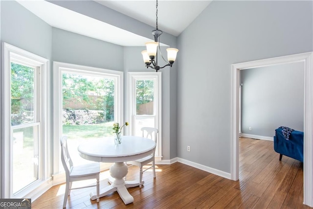 dining room with hardwood / wood-style flooring, vaulted ceiling, and a notable chandelier